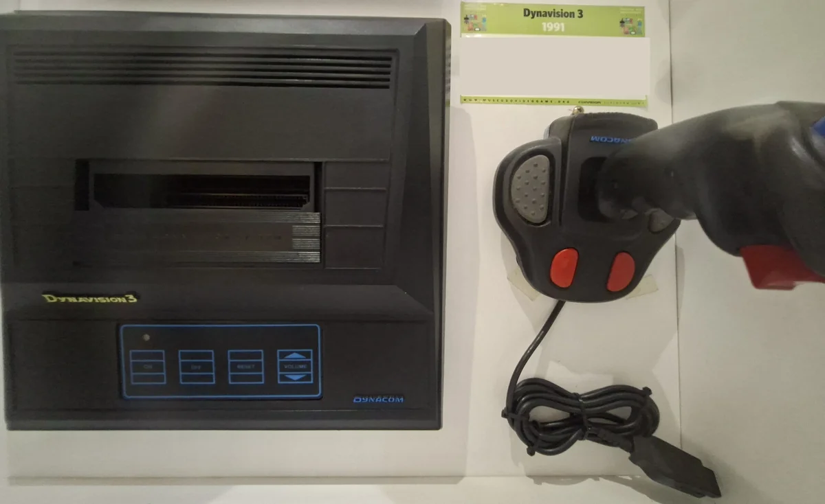 Console Dynavision 3 da Dynacom, preto, com slot superior e controle híbrido, etiqueta de museu Dynavision 3 1991