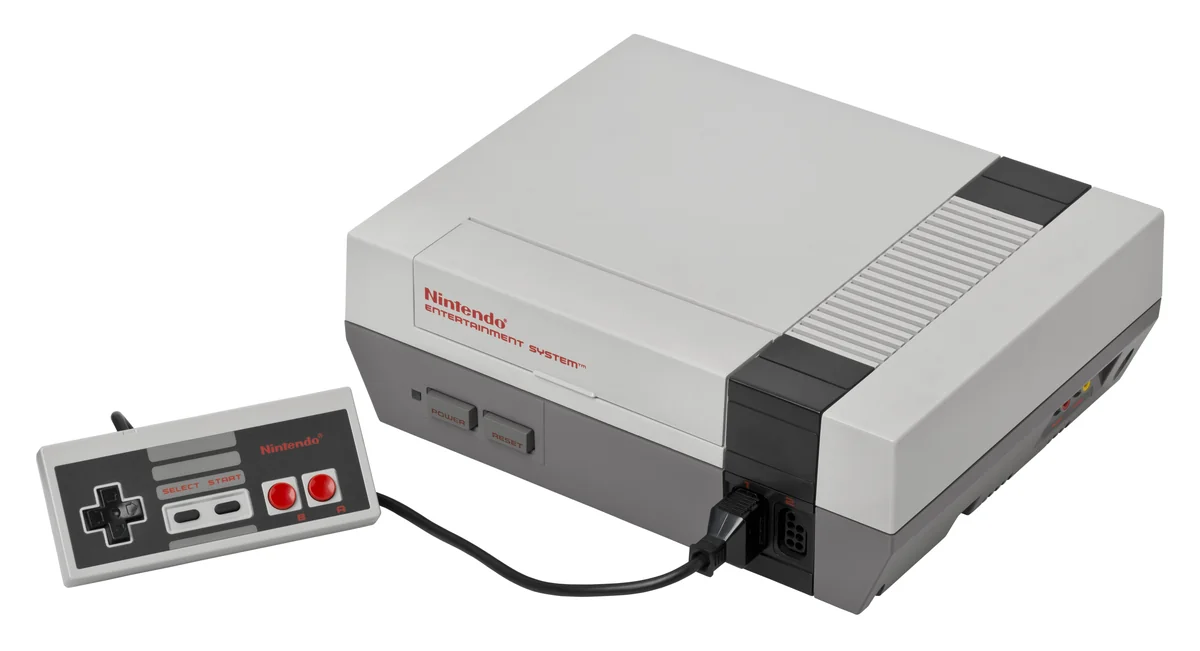 NES-001 visto de frente com um controle cinza conectado, fundo branco de estúdio