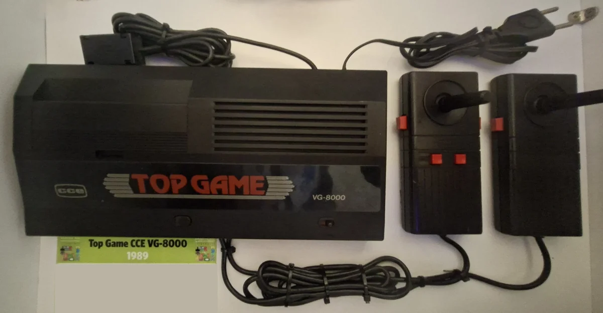 Console preto Top Game CCE VG-8000 com dois joysticks pretos de haste e etiqueta de museu 1989