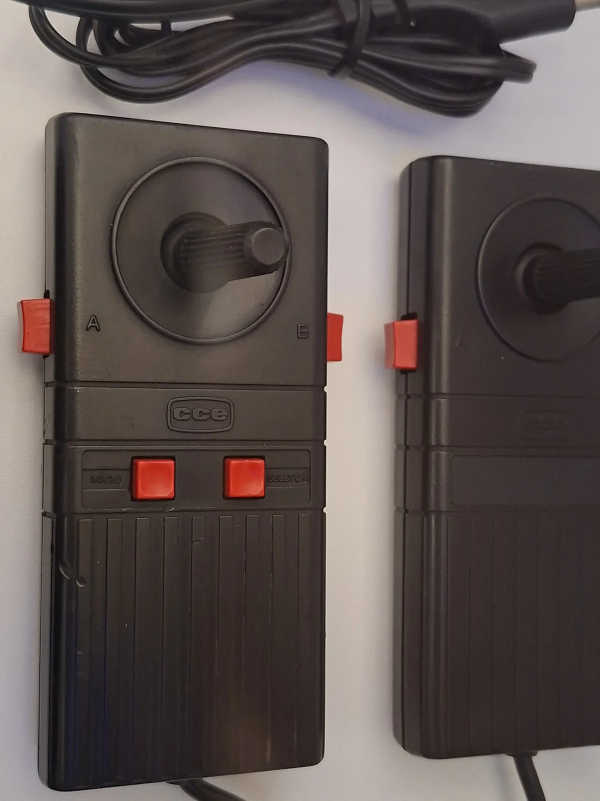 Dois controles pretos do Top Game CCE com mini joystick, botões vermelhos Início e Seletor